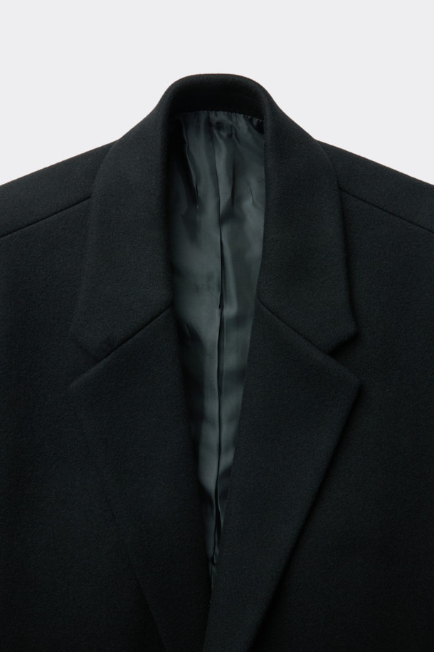 남성용 블랙 오버사이즈 핏 노치드 라펠 코트입니다. 가을, 겨울 시즌에 어울리는 두꺼운 두께감으로, 울, 나일론, 캐시미어 혼방 소재로 제작되어 부드러운 촉감과 보온성을 제공합니다. 미니멀, 클래식 스타일을 기반으로 하여 출근룩, 오피스룩, 모임룩 등 다양한 TPO에 활용 가능합니다. 싱글 버튼 여밈 방식과 롱 기장, 긴 소매 디자인으로 시크한 매력을 더하며, 오버핏으로 편안한 착용감을 선사합니다.
