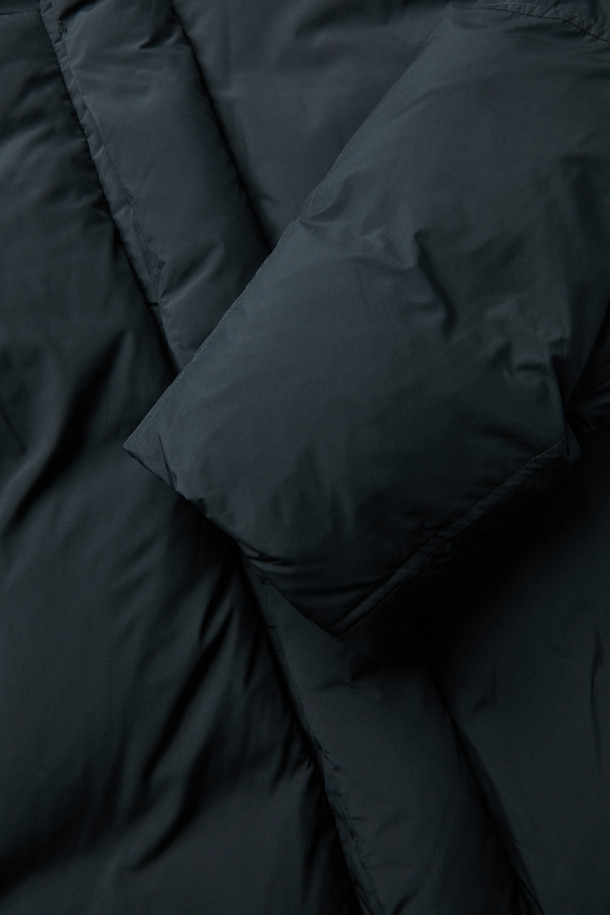 세련된 블랙 후드 숏 다운 재킷입니다. 겨울철 데일리룩에 어울리는 미니멀한 스타일의 이 재킷은 숏패딩 디자인으로 크롭 기장을 자랑합니다. 부드러운 촉감의 폴리에스테르 소재에 구스다운 80:20 충전재를 사용하여 보온성을 높였습니다. 2-Way 지퍼와 히든 여밈 방식으로 깔끔함을 더했으며, 오버핏으로 편안한 착용감을 선사합니다. 경량 소재에 은은한 광택감이 더해져 시크한 매력을 줍니다.
