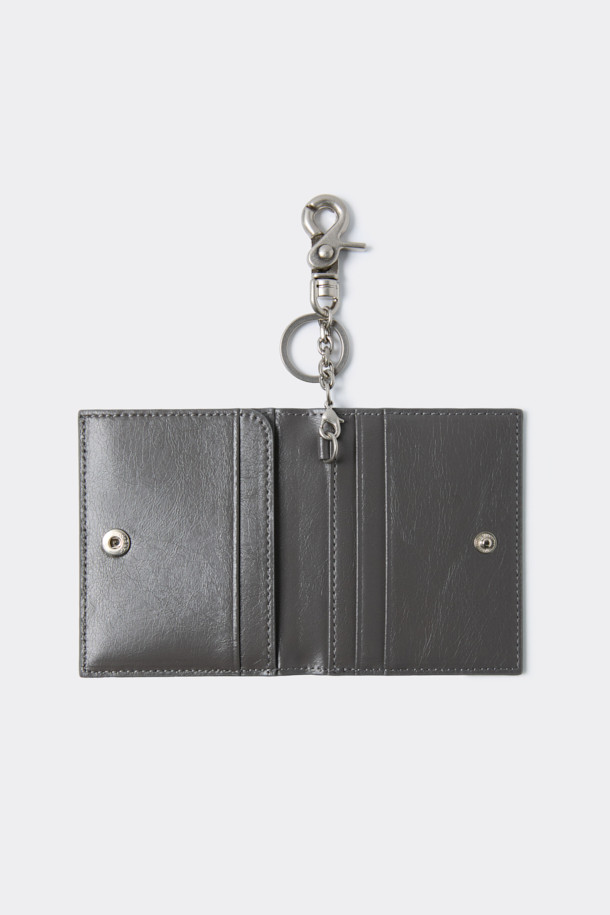 세련된 그레이 색상의 폴딩 카드지갑입니다. 미니멀한 디자인에 합성가죽 소재로 제작되어 데이트룩, 쇼핑룩, 카페룩 등 다양한 TPO에 활용하기 좋습니다. 컴팩트한 사이즈로 휴대성이 뛰어나며, 내부에는 카드 포켓 4칸과 날개 오픈포켓 1칸이 있어 수납력을 높였습니다. 또한, 로고 바 디자인 장식과 탈부착 가능한 키링으로 포인트를 더해 시크하고 클래식한 스타일을 연출합니다. 오픈형 잠금방식으로 편리하게 사용 가능합니다.

