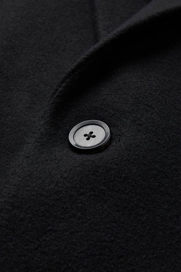 블랙 캐시미어 블렌디드 싱글 코트는 남성 고객을 위한 가을/겨울용 아우터입니다. 울, 캐시미어, 폴리에스테르, 나일론, 레이온, 코튼 등 다양한 소재를 혼방하여 부드러운 촉감과 두꺼운 두께를 자랑합니다. 클래식하고 미니멀한 스타일로, 오피스룩, 비즈니스 캐주얼, 모임룩 등 TPO에 맞춰 시크하게 연출할 수 있습니다. 너치드 라펠, 2버튼, 사이드 다트, 숄더 다트, 어깨 패드, 포켓 스티치 디테일이 돋보이는 레귤러핏 싱글 코트입니다. 긴 소매 기장의 무지 디자인으로 어떤 스타일에도 쉽게 매치할 수 있습니다.
