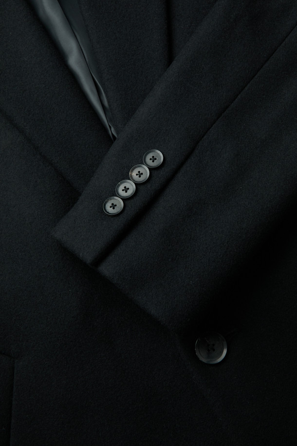 남성용 블랙 오버사이즈 핏 노치드 라펠 코트입니다. 가을, 겨울 시즌에 어울리는 두꺼운 두께감으로, 울, 나일론, 캐시미어 혼방 소재로 제작되어 부드러운 촉감과 보온성을 제공합니다. 미니멀, 클래식 스타일을 기반으로 하여 출근룩, 오피스룩, 모임룩 등 다양한 TPO에 활용 가능합니다. 싱글 버튼 여밈 방식과 롱 기장, 긴 소매 디자인으로 시크한 매력을 더하며, 오버핏으로 편안한 착용감을 선사합니다.
