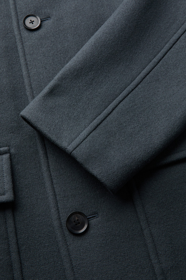 세련된 남성분들을 위한 그레이 울 카코트입니다. 울과 나일론 혼방 소재로 제작되어 가을, 겨울 시즌에 따뜻하고 편안하게 착용할 수 있습니다. 미니멀하고 클래식한 디자인으로 출근룩, 비즈니스 캐주얼, 모임룩 등 다양한 TPO에 활용 가능합니다. 오버핏 실루엣과 싱글 버튼 여밈, 아웃포켓 디테일이 돋보이며, 긴 소매 기장으로 더욱 시크한 분위기를 연출합니다. 무지 패턴의 그레이 컬러는 어떤 스타일에도 쉽게 매치되어 활용도가 높습니다.
