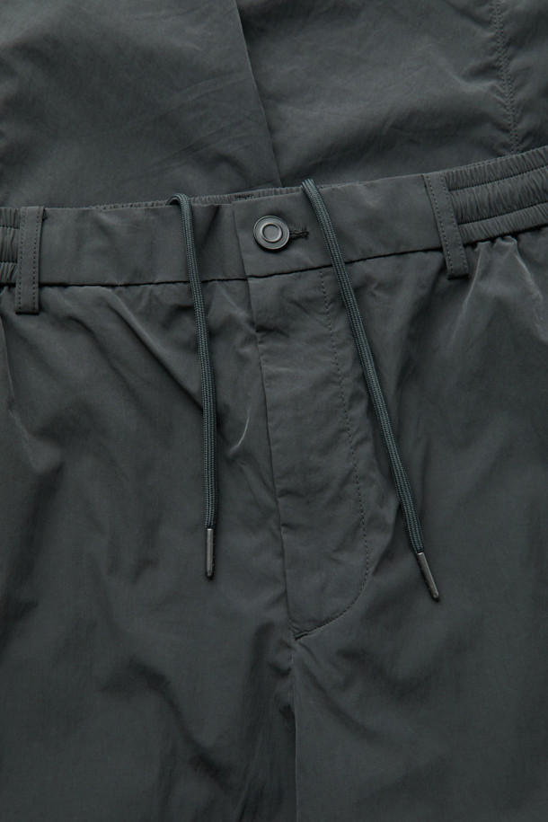 다크그레이 컬러의 Grey 사이드 지퍼 디테일 팬츠입니다. 나일론과 폴리에스테르 혼방 소재로 제작되어 사계절 내내 착용 가능하며, 은은한 광택감이 특징입니다. 와이드핏으로 편안한 착용감을 선사하며, 앞뒤 절개 디테일과 사이드 2-Way 지퍼 디테일로 포인트를 더했습니다. 하프 밴딩과 스트링으로 허리 조절이 용이하며, 출근룩, 비즈니스 캐주얼, 미니멀, 스포티, 캐주얼 스타일 모두 소화 가능한 활용도 높은 아이템입니다.
