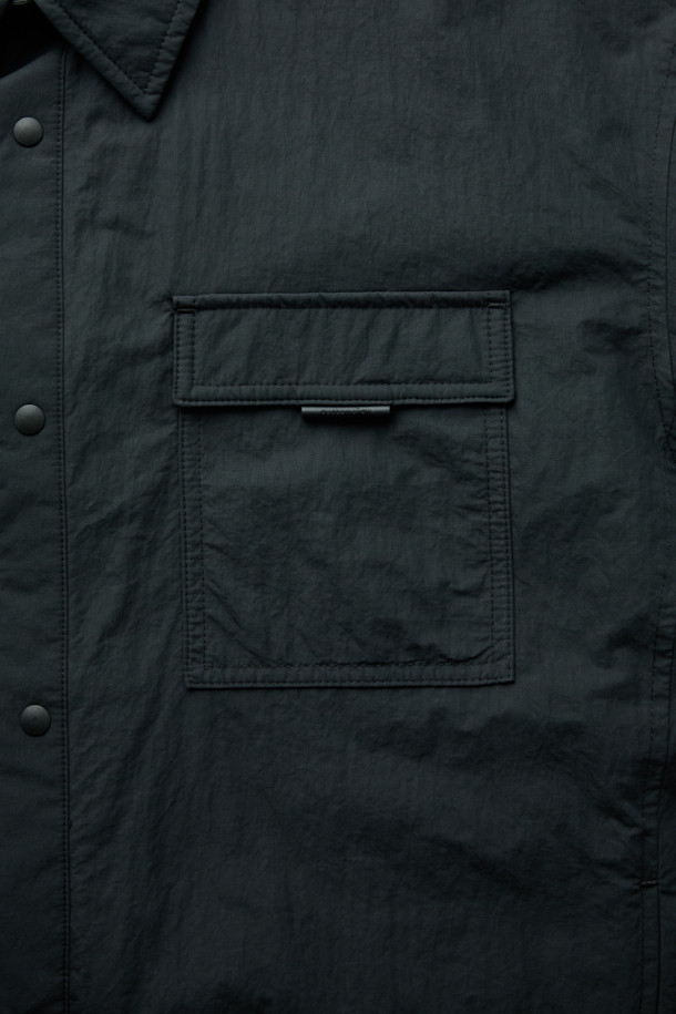 블랙 패딩 아우터 셔츠는 남성용 캐주얼 패딩셔츠입니다. 가을과 겨울에 착용하기 좋으며, 차이나칼라와 긴 소매, 무지 패턴으로 미니멀한 스타일을 연출합니다. 초경량 하스 충전재를 사용하여 보온성을 높였으며, 퀼팅 안감으로 부드러운 착용감을 제공합니다. 밑단 스트링 디테일과 우레탄 라벨 포인트가 특징이며, 핏은 오버핏으로 제작되었습니다. 면과 나일론 혼방 소재로 제작되어 편안함과 내구성을 동시에 갖췄습니다.
