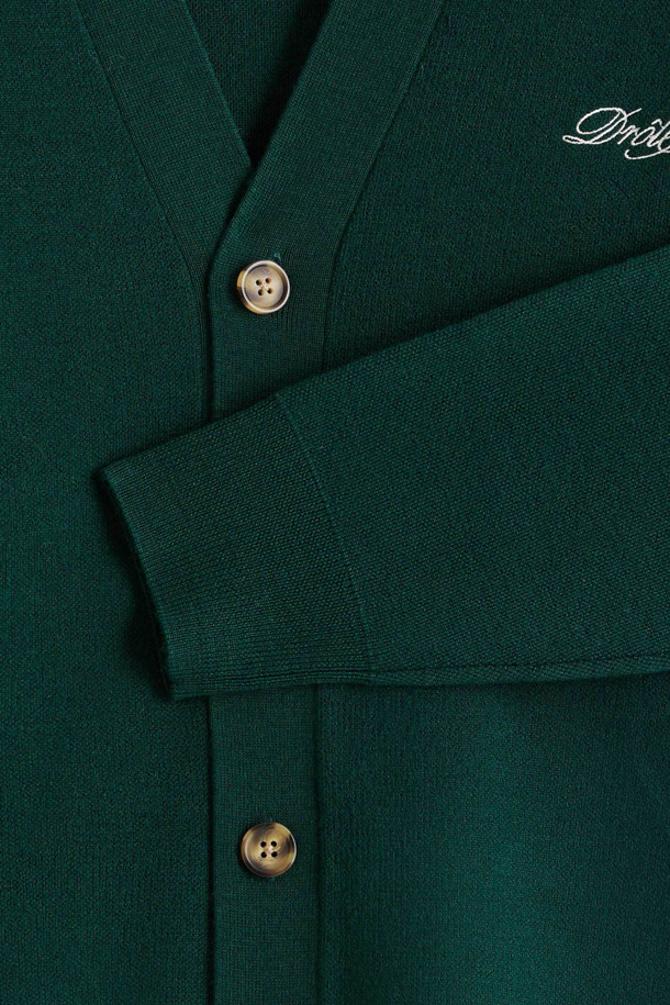 "재미있는 카디건" (르 카디건 드롤)은 부드러운 울 소재의 남녀 공용 가을/겨울용 니트 카디건입니다. 클래식하고 베이직한 스타일로, 짙은 그린 및 그린 컬러로 제공됩니다. 가슴 부분의 '재미있는' 자수 디테일이 돋보이며, 레귤러 핏과 V넥 디자인으로 제작되었습니다. 5버튼 여밈과 리브드 트리밍, 긴 소매가 특징이며, 데이트룩과 겨울 데일리룩에 활용하기 좋습니다.