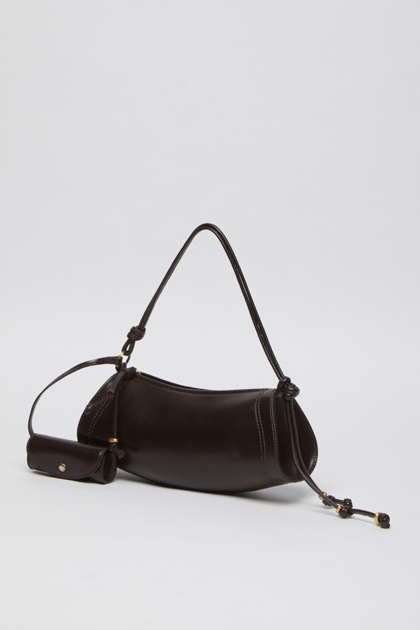 에스프레소 컬러의 Knotted case bag(노티드 케이스 백)은 부드러운 가죽 소재의 여성용 크로스백입니다. 미디엄 사이즈의 반원 형태에 매듭 디테일과 버클 장식이 포인트이며, 세련된 세미 크레센트 쉐입이 돋보입니다. 지퍼형 잠금 방식으로 소지품을 안전하게 보관할 수 있으며, 숄더 스트랩이 포함되어 있어 편리하게 착용 가능합니다. 클래식, 미니멀, 시크 스타일을 즐기는 분들에게 데이트룩, 모임룩, 출근룩 등 다양한 TPO에 맞춰 활용하기 좋은 아이템입니다.
