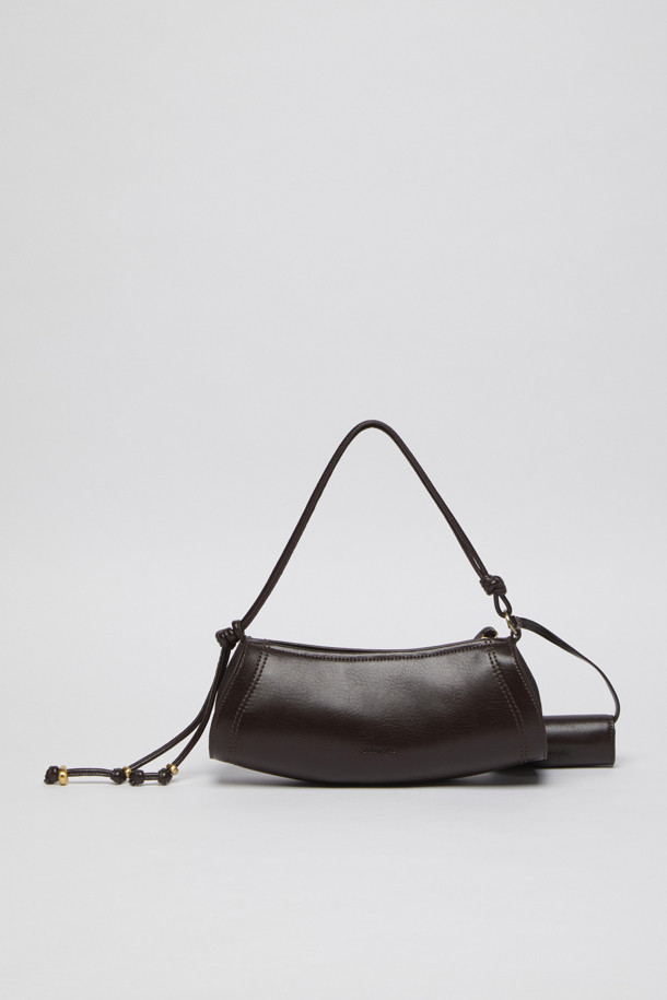 에스프레소 컬러의 Knotted case bag(노티드 케이스 백)은 부드러운 가죽 소재의 여성용 크로스백입니다. 미디엄 사이즈의 반원 형태에 매듭 디테일과 버클 장식이 포인트이며, 세련된 세미 크레센트 쉐입이 돋보입니다. 지퍼형 잠금 방식으로 소지품을 안전하게 보관할 수 있으며, 숄더 스트랩이 포함되어 있어 편리하게 착용 가능합니다. 클래식, 미니멀, 시크 스타일을 즐기는 분들에게 데이트룩, 모임룩, 출근룩 등 다양한 TPO에 맞춰 활용하기 좋은 아이템입니다.
