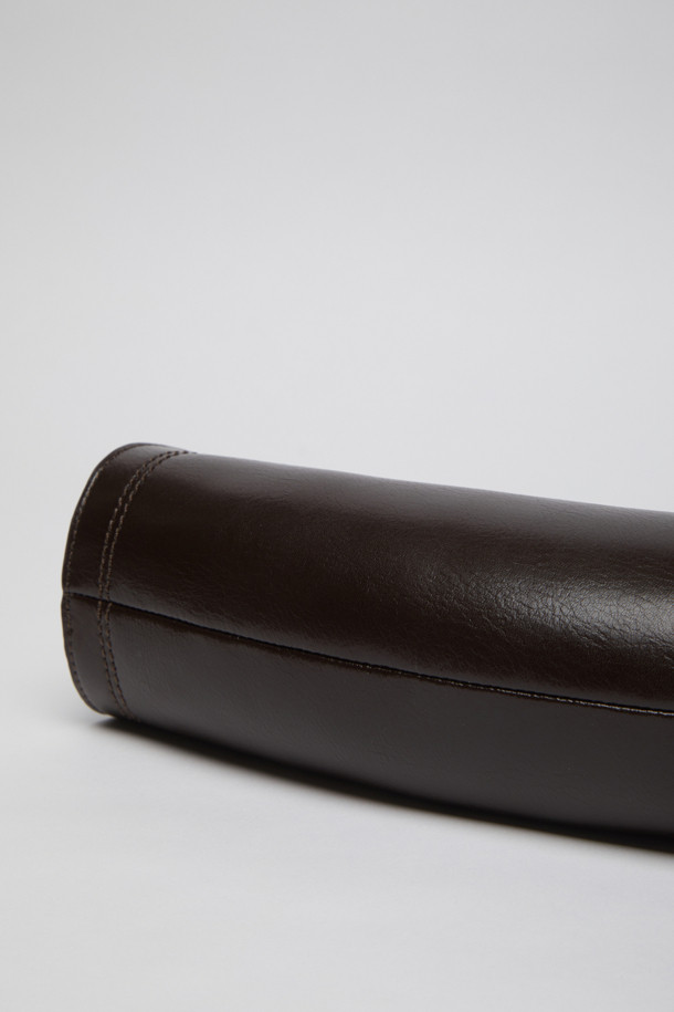 에스프레소 컬러의 Knotted case bag(노티드 케이스 백)은 부드러운 가죽 소재의 여성용 크로스백입니다. 미디엄 사이즈의 반원 형태에 매듭 디테일과 버클 장식이 포인트이며, 세련된 세미 크레센트 쉐입이 돋보입니다. 지퍼형 잠금 방식으로 소지품을 안전하게 보관할 수 있으며, 숄더 스트랩이 포함되어 있어 편리하게 착용 가능합니다. 클래식, 미니멀, 시크 스타일을 즐기는 분들에게 데이트룩, 모임룩, 출근룩 등 다양한 TPO에 맞춰 활용하기 좋은 아이템입니다.
