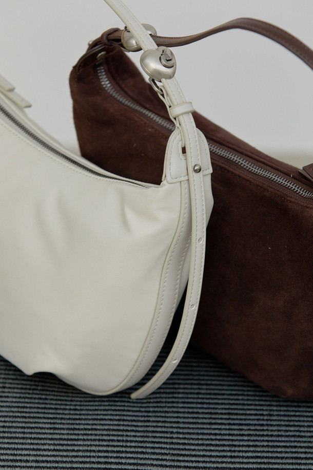 Luv moon bag(스웨이드 브라운)은 부드러운 스웨이드와 양가죽 소재로 제작되어 매트한 질감과 자연스러운 주름이 돋보이는 미디엄 사이즈의 호보백입니다. 미니멀하고 캐주얼한 스타일에 잘 어울리며, 하트 스토퍼와 슬라이더 디자인 장식이 특징입니다. 반원 모양에 오픈형 잠금 방식을 채택하여 편안하게 사용할 수 있으며, 사이즈 조절이 가능합니다. 데일리 백으로 활용하기 좋으며, 털 빠짐 현상과 수분에 취약하니 주의하여 사용해야 합니다. 더스트백이 포함되어 있습니다.
