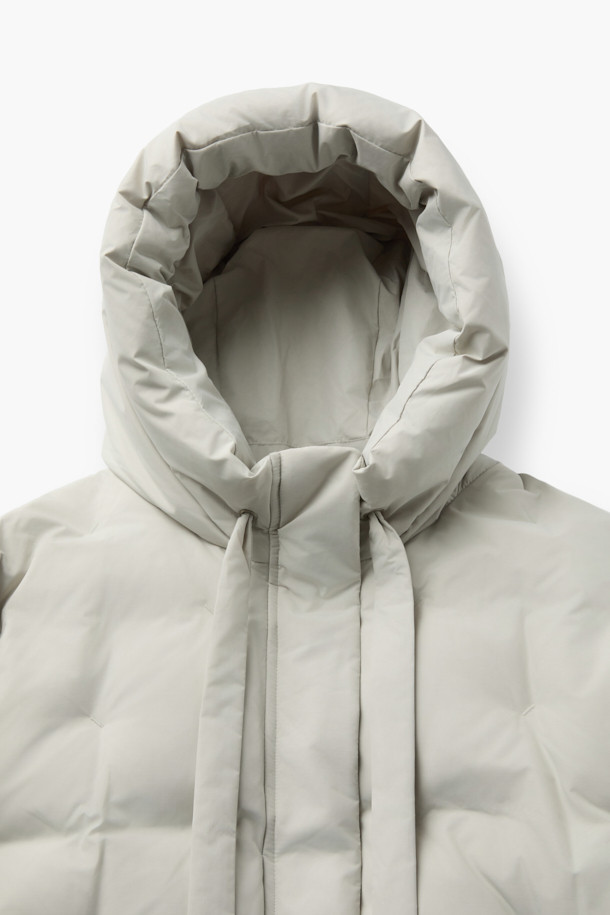 [epigram여성] 후드 스티치 숏 다운은 미니멀한 스타일의 여성용 숏패딩입니다. 하이넥 디자인과 후드가 있어 방풍 및 보온 기능이 뛰어나 겨울철 일상룩과 여행룩에 적합합니다. 덕다운 충전재와 부드러운 촉감으로 편안한 착용감을 선사하며, 오버핏으로 여유로운 실루엣을 연출합니다. 지퍼와 스냅 여밈 방식, 히든 포켓, 소매 엘라스틱 밴딩, 밑단 밴딩, 드로우스트링 등의 디테일이 돋보이며, 화이트 컬러에 무지 패턴으로 다양한 스타일에 매치하기 좋습니다. 
