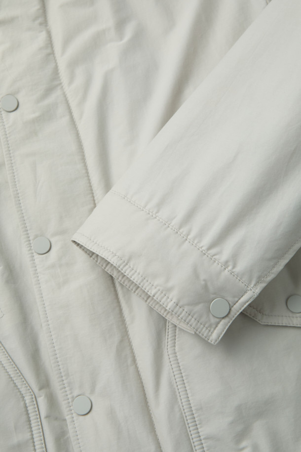 일상과 출근룩에 모두 잘 어울리는 셔츠형 패디드 점퍼입니다. 면과 나일론 혼방 소재로 제작되어 부드러운 촉감과 가벼운 착용감을 선사하며, 초겨울 날씨에 적합합니다. 셔츠 디자인에 히든 플래킷과 스냅 버튼 여밈 방식을 적용하여 클래식하고 미니멀한 스타일을 연출합니다. 독일 프라우덴사의 comfortemp 패딩 충전재와 생활 방수 기능, 드로우스트링 밑단, 큼직한 전면 포켓, 카라 디자인, 다트와 패널 디테일 등 다양한 특징을 갖추었습니다. 여유 있는 핏으로 편안함까지 더했습니다.
