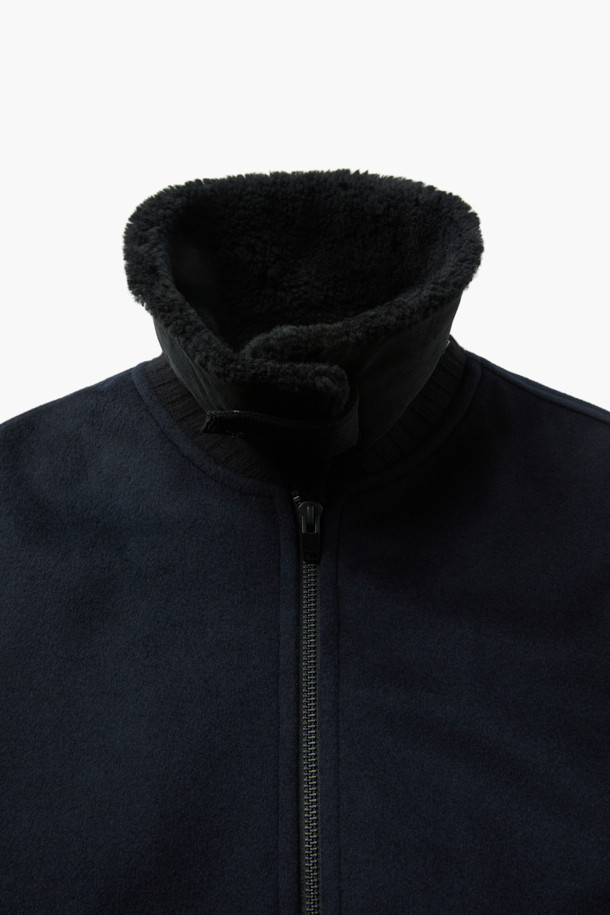 FUR 디테쳐블 울 블루종 점퍼는 클래식한 무드의 겨울철 남성 아우터입니다. 네이비 컬러의 숏 기장 블루종으로, 탈부착 가능한 FUR(퍼) 디테쳐블 카라가 특징입니다. 보온성을 높여주는 퀄팅 안감과 패딩 안감, 부드러운 촉감의 울 소재를 사용하여 제작되었습니다. 니트 소매단과 밑단 마감으로 편안함을 더했으며, 집업 스타일과 루즈핏으로 출근룩과 비즈니스 캐주얼에 활용하기 좋습니다.
