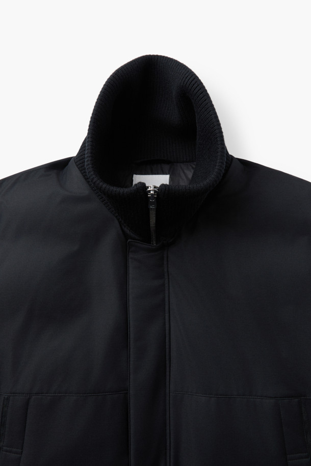 로로피아나(Loro Piana) 패브릭 미들 다운 점퍼는 포멀과 캐주얼 스타일을 아우르는 블랙 컬러의 겨울철 필수 아우터입니다. 울과 나일론 혼방 소재로 제작되어 부드러운 촉감과 뛰어난 보온성을 제공하며, 방수 및 방풍 기능을 갖춰 여행이나 일상생활에서 활용하기 좋습니다. 릴랙스핏과 오버핏으로 편안한 착용감을 선사하며, 구스다운 90%와 깃털 10%의 충전재, 필파워 650~700으로 뛰어난 보온성을 자랑합니다. 울 리브 니트 카라와 소매, 히든 스냅 여밈, 배색 테이프 디테일이 고급스러움을 더합니다.
