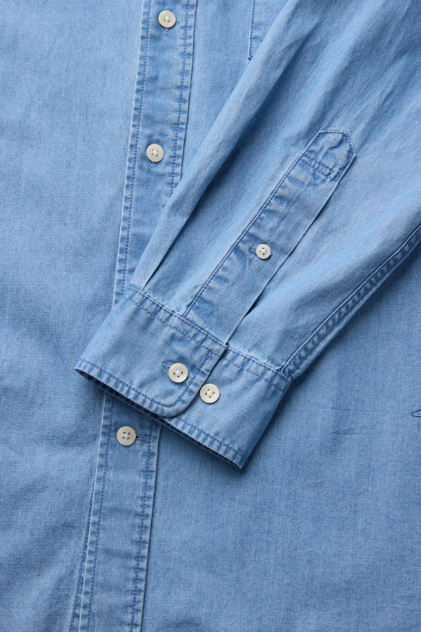 연청 컬러의 데님 코튼 셔츠입니다. 면과 데님 혼방의 NF21사 수입 원단을 사용하여 부드러운 촉감을 선사합니다. 얇은 두께감으로 사계절 내내 활용 가능하며, 차이나 칼라와 세미오버핏으로 캐주얼한 스타일을 연출할 수 있습니다. 드롭 숄더 디자인과 패치 포켓 디테일이 특징이며, 미니멀, 클래식 스타일을 선호하는 분들께 추천합니다. 긴 소매 기장의 무지 셔츠로 다양한 룩에 활용하기 좋습니다.
