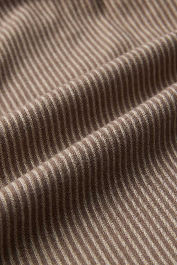 [epigram(에피그램) 여성] 플란넬 스트라이프 셔츠는 부드러운 플란넬 소재로 제작되어 겨울철에도 따뜻하게 착용할 수 있습니다. 멜란지 브라운과 화이트 컬러의 스트라이프 패턴이 베이직하면서도 클래식한 분위기를 연출합니다. 루즈핏으로 편안함을 더하고, 긴소매와 칼라 디자인으로 포멀한 느낌을 줍니다. 반오픈 스타일과 싸개 단추 마감, 뒷면 셔링 디테일이 돋보이며, 겨울 데일리룩이나 카페룩에 잘 어울립니다.
