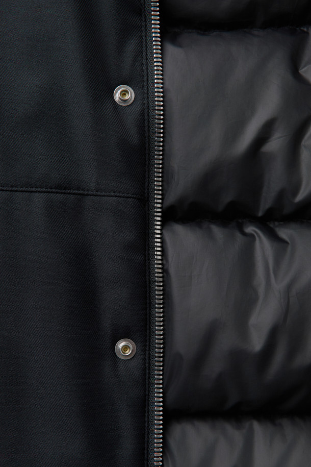 로로피아나(Loro Piana) 패브릭 미들 다운 점퍼는 포멀과 캐주얼 스타일을 아우르는 블랙 컬러의 겨울철 필수 아우터입니다. 울과 나일론 혼방 소재로 제작되어 부드러운 촉감과 뛰어난 보온성을 제공하며, 방수 및 방풍 기능을 갖춰 여행이나 일상생활에서 활용하기 좋습니다. 릴랙스핏과 오버핏으로 편안한 착용감을 선사하며, 구스다운 90%와 깃털 10%의 충전재, 필파워 650~700으로 뛰어난 보온성을 자랑합니다. 울 리브 니트 카라와 소매, 히든 스냅 여밈, 배색 테이프 디테일이 고급스러움을 더합니다.
