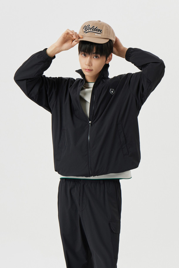 **스탠드 칼라 윈드브레이커**는 봄, 여름, 가을 간절기에 활용하기 좋은 아우터입니다. 베이지와 블랙 두 가지 색상으로 출시되었으며, 스포티한 무드를 연출합니다. 슬림핏, 데일리핏, 오버핏 세 가지 핏으로 제공되어 다양한 스타일을 소화할 수 있습니다. 신축성이 뛰어난 스트레치 소재와 스트레치 안감을 사용하여 편안한 착용감을 선사합니다. 스탠드 칼라, 전면 사선 싱글월트 포켓, 후면 골드베어 라인 로고 프린트, 소매단 밴드, 밑단 스트링 & 스토퍼 등의 디자인 디테일이 돋보이며, 동네 마실룩, 산책룩, 여행룩 등 다양한 TPO에 어울리는 활용도 높은 아이템입니다.
