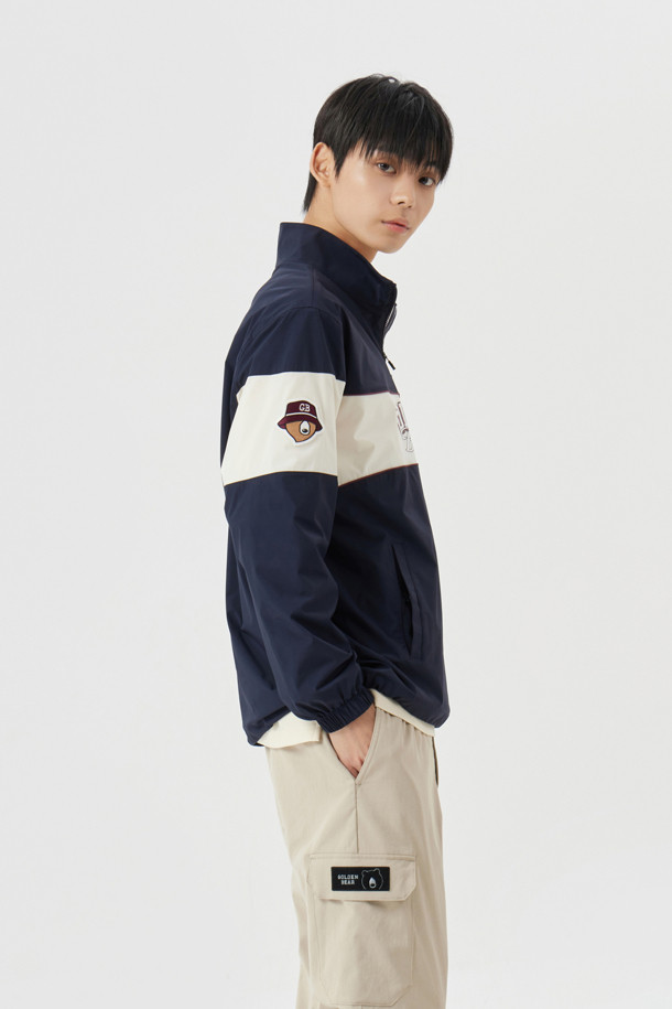 컨트라스트 체스트 보더 우븐 아노락(Contrast Chest Border Woven Anorak)은 남성용 아우터 아노락입니다. 아이보리, 민트, 네이비 세 가지 색상으로 출시되었으며, 봄, 가을, 겨울 계절에 골프 및 일상용으로 착용하기 좋습니다. 가슴 중앙에서 소매로 이어지는 보더 라인과 세미오토락 지퍼풀러가 돋보이며, 넥밴드 이면의 포인트 컬러, 오른쪽 소매의 베어 자수 와펜으로 포인트를 더했습니다. 슬림핏과 오버핏 두 가지 핏으로 출시되었으며, 나일론 소재에 두꺼운 두께감, 메쉬 안감, 긴 소매 기장으로 제작되었습니다. 가슴 하단의 사선 싱글월트 포켓, 소매단 밴드, 밑단 스트링 & 스토퍼, 후면 하단 장갑 벨크로 등 다양한 디테일이 특징입니다.
