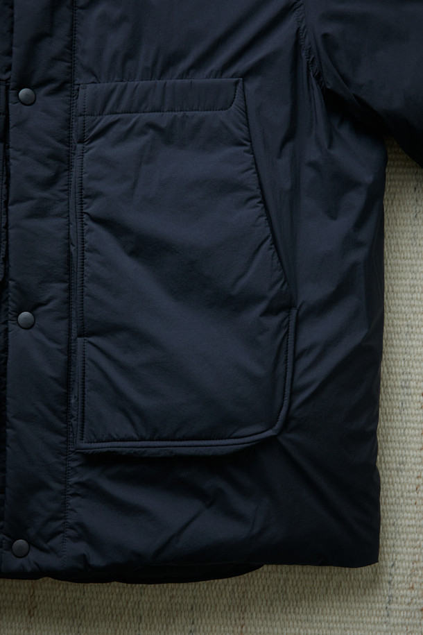 FFC x DOCUMENT (FFC x 도큐먼트) 피셔맨 셔팅 구스 다운 재킷은 겨울철 데일리룩을 위한 미니멀하고 클래식한 스타일의 아우터입니다. 블랙 컬러에 무지 디자인으로 어떤 옷에도 쉽게 매치할 수 있으며, 셔츠형 코트 타입으로 세련된 느낌을 더했습니다. 90/10 구스다운 충전재와 경량 소재를 사용하여 보온성과 편안한 착용감을 제공하며, 루즈핏으로 여유로운 실루엣을 연출합니다. 입체 포켓과 여유있는 어깨라인이 특징이며, 투웨이 지퍼 여밈 방식으로 실용성을 높였습니다.
