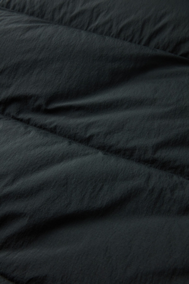 세미 오버핏으로 편안하게 착용 가능한 퀼팅 다운 점퍼입니다. 겨울철 추위를 막아주는 두꺼운 두께감과 보온 및 방풍 기능으로 따뜻함을 제공합니다. 부드러운 촉감의 나일론 소재와 블랙 컬러의 무지 디자인으로 캐주얼, 미니멀, 클래식 등 다양한 스타일 연출에 활용할 수 있습니다. 멀티 포켓, 지퍼 테이프 부분 노출, 밑단 스트링, 내장 후드, 벨보아 넥 안감, 이너 커프스 엘라스틱 밴드, 머스코비 다운 충전재 등 디테일이 돋보입니다. 출근룩, 여행룩 등 일상에서 폭넓게 활용 가능하며, 긴 소매와 지퍼형 여밈 방식으로 편의성을 더했습니다.
