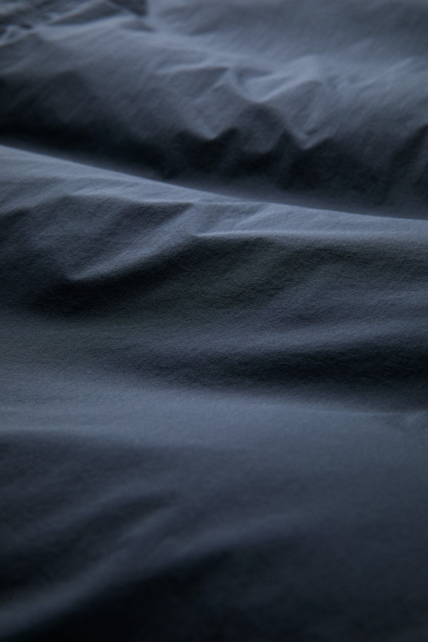 FFC x DOCUMENT (FFC x 도큐먼트) 피셔맨 셔팅 구스 다운 재킷은 겨울철 데일리룩을 위한 미니멀하고 클래식한 스타일의 아우터입니다. 블랙 컬러에 무지 디자인으로 어떤 옷에도 쉽게 매치할 수 있으며, 셔츠형 코트 타입으로 세련된 느낌을 더했습니다. 90/10 구스다운 충전재와 경량 소재를 사용하여 보온성과 편안한 착용감을 제공하며, 루즈핏으로 여유로운 실루엣을 연출합니다. 입체 포켓과 여유있는 어깨라인이 특징이며, 투웨이 지퍼 여밈 방식으로 실용성을 높였습니다.
