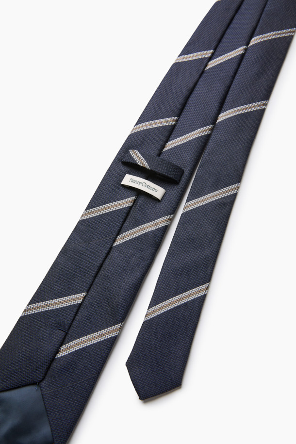 네이비 레지멘탈 타이는 남성용 넥타이로, 가을과 겨울에 착용하기 좋은 아이템입니다. 네이비, 브라운, 화이트 컬러가 조화롭게 어우러진 스트라이프 패턴의 레지멘탈 디자인이 특징이며, 클래식한 분위기를 연출합니다. 실크와 폴리에스테르 혼방 소재로 제작되어 은은한 광택과 부드러운 매끄러운 촉감을 선사하며, 8cm 너비로 제작되었습니다. 내구성이 뛰어나고 관리가 용이하며, 네트 조직감과 입체감 있는 표면으로 고급스러움을 더해 오피스룩, 비즈니스 캐주얼, 회의룩 등 다양한 TPO에 활용하기 좋습니다.
