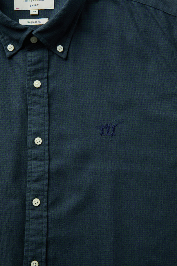 네이비와 그린 컬러로 구성된 마이크로 하운드투스 셔츠입니다. 잦은 마찰에도 튼튼한 트윌 원단에 코튼 100% 소재, 기모 처리로 부드러운 촉감을 선사합니다. 레귤러핏으로 제작되어 편안한 착용감을 제공하며, 버튼다운 네크라인과 긴 소매 기장으로 클래식한 스타일을 연출합니다. 가슴 부분에는 로고 자수 디테일이, 뒷면에는 요크 주름 디테일이 더해져 완성도를 높였습니다. 겨울철 데일리룩, 출근룩, 비즈니스 캐주얼 스타일을 위한 미니멀하고 클래식한 셔츠입니다.
