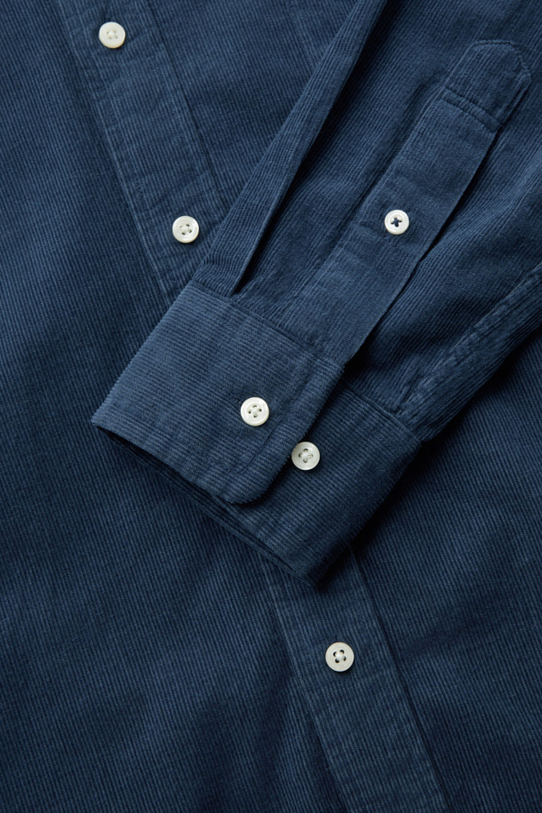 터키 KIPAS사의 수입 코듀로이 원단을 사용한 [Imported Fabric] 코듀로이 솔리드 셔츠 (컴포트핏)입니다. 톤온톤 네이비 컬러의 투톤 배색이 특징이며, 버튼다운 카라 디자인으로 클래식한 분위기를 연출합니다. 가슴 포켓과 뒷면 요크 주름 디테일이 돋보이며, 헨리코튼 라벨로 고급스러움을 더했습니다. 겨울철 비즈니스 캐주얼 및 데일리룩에 활용하기 좋은 긴소매 셔츠입니다. 컴포트핏으로 편안한 착용감을 선사합니다.
