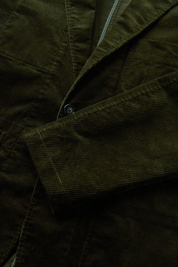 **코튼 코듀로이 재킷**은 부드러운 코듀로이 소재와 면 혼방으로 제작되어 가을, 겨울철 따뜻하고 편안한 착용감을 선사합니다. 릴랙스핏으로 제작되어 활동성이 뛰어나며, 캐주얼, 클래식, 미니멀 스타일을 모두 소화할 수 있습니다. 그린 컬러의 무지 디자인에 아웃포켓 디테일, 싱글 벤트, 컨버터블 카라가 더해져 세련된 느낌을 줍니다. 출근룩이나 모임룩 등 다양한 TPO에 활용 가능하며, 싱글 버튼 방식의 블레이저 타입 재킷입니다. 긴 소매 기장과 두꺼운 두께감으로 보온성을 높였습니다.
