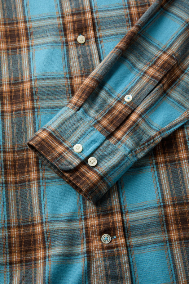 블루와 오렌지, 브라운, 화이트 컬러 배색의 체크 패턴이 돋보이는 셔츠입니다. 부드러운 촉감의 면 100% 트윌 원단으로 제작되어 겨울철에도 따뜻하게 착용할 수 있습니다. 가슴 부분에는 로고 자수 디테일이, 뒷면 요크에는 주름 디테일이 더해져 캐주얼하면서도 클래식한 무드를 연출합니다. 버튼다운 카라와 컴포트 핏으로 제작되어 출근룩이나 비즈니스 캐주얼 스타일에도 활용 가능하며, 미니멀한 스타일을 즐기는 분들께도 추천합니다. 긴 소매 기장으로 다양한 레이어드 연출이 용이합니다.
