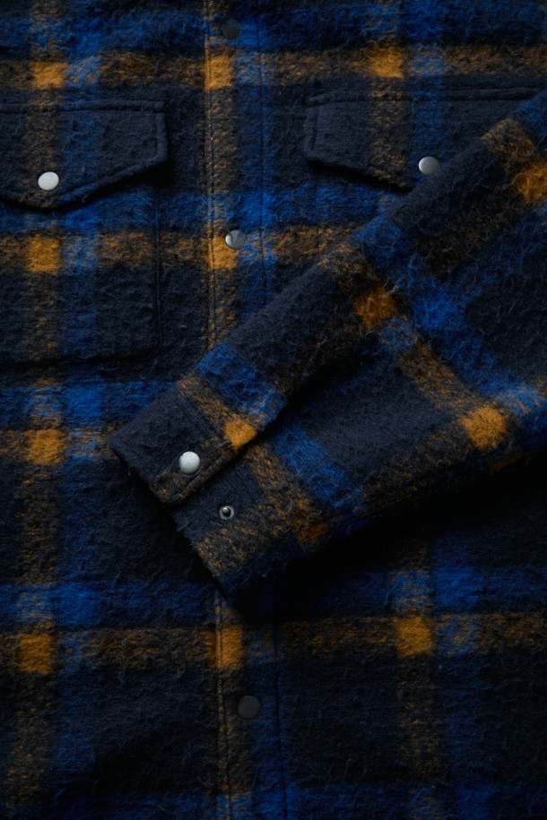 [Fly Fishing Club] 카젠티노 피싱 셔츠는 가을, 겨울에 어울리는 남성용 셔츠형 아우터입니다. 네이비, 로열블루, 오렌지 세 가지 색상으로 출시되었으며, 빈티지, 아웃도어, 워크웨어 스타일을 아우르는 매력을 지닙니다. 울 소재에 두꺼운 두께감과 부클 촉감을 더해 보온성을 높였으며, 긴 소매와 세미 루즈핏으로 편안한 착용감을 선사합니다. 체크 패턴과 체스트 포켓, 사선 핸드 포켓, D-링 디테일, 코듀로이 포켓 배색 등의 특징이 돋보이며, 스냅 여밈 방식과 생활 발수 기능으로 실용성을 더했습니다. 캠핑룩, 가을 나들이룩, 겨울 데일리룩 등 다양한 TPO에 워크웨어, 클래식, 캐주얼 무드로 활용하기 좋습니다.
