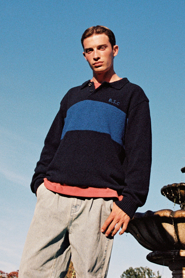 **British Sporting Club 컬러 블록 폴로 니트**

네이비와 블루 컬러 배색이 돋보이는 [British Sporting Club] (브리티시 스포팅 클럽)의 컬러 블록 폴로 니트입니다. 부드러운 촉감의 부클사 니트 소재로 제작되어 가을 시즌에 따뜻하게 착용하기 좋습니다. 루즈핏으로 편안하며, 긴 소매와 폴로넥 디자인이 클래식하면서도 스포티한 무드를 연출합니다. 가슴 부분에는 B.S.C 자수 로고가, 소매와 밑단은 립 조직 마감으로, 단추 여밈 디테일이 돋보입니다. 데이트룩, 카페룩, 가을 나들이룩 등 다양한 스타일링에 활용해 보세요.
