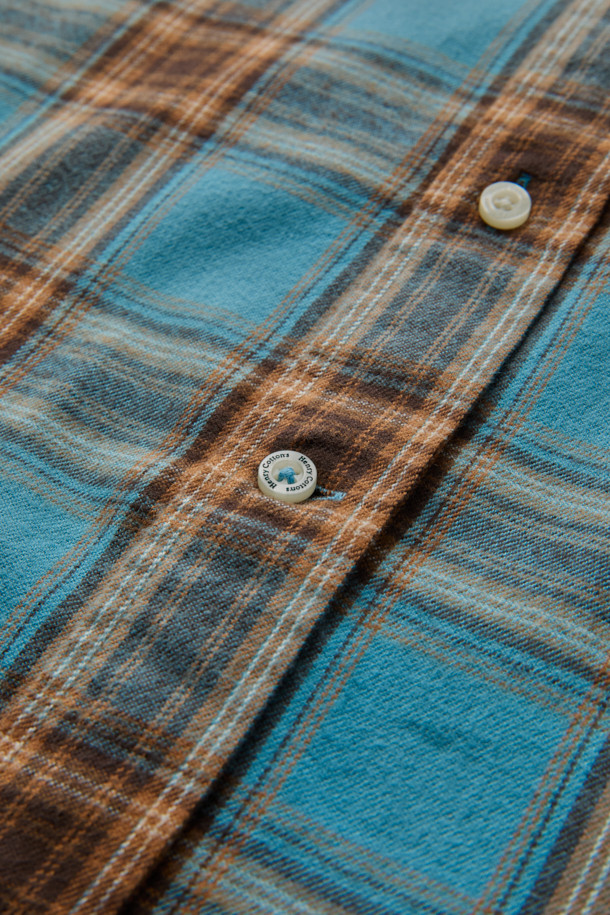 블루와 오렌지, 브라운, 화이트 컬러 배색의 체크 패턴이 돋보이는 셔츠입니다. 부드러운 촉감의 면 100% 트윌 원단으로 제작되어 겨울철에도 따뜻하게 착용할 수 있습니다. 가슴 부분에는 로고 자수 디테일이, 뒷면 요크에는 주름 디테일이 더해져 캐주얼하면서도 클래식한 무드를 연출합니다. 버튼다운 카라와 컴포트 핏으로 제작되어 출근룩이나 비즈니스 캐주얼 스타일에도 활용 가능하며, 미니멀한 스타일을 즐기는 분들께도 추천합니다. 긴 소매 기장으로 다양한 레이어드 연출이 용이합니다.
