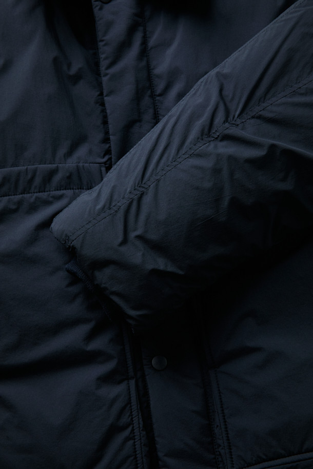 FFC x DOCUMENT (FFC x 도큐먼트) 피셔맨 셔팅 구스 다운 재킷은 겨울철 데일리룩을 위한 미니멀하고 클래식한 스타일의 아우터입니다. 블랙 컬러에 무지 디자인으로 어떤 옷에도 쉽게 매치할 수 있으며, 셔츠형 코트 타입으로 세련된 느낌을 더했습니다. 90/10 구스다운 충전재와 경량 소재를 사용하여 보온성과 편안한 착용감을 제공하며, 루즈핏으로 여유로운 실루엣을 연출합니다. 입체 포켓과 여유있는 어깨라인이 특징이며, 투웨이 지퍼 여밈 방식으로 실용성을 높였습니다.
