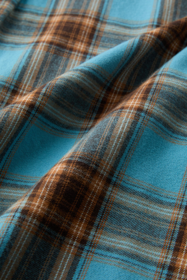 블루와 오렌지, 브라운, 화이트 컬러 배색의 체크 패턴이 돋보이는 셔츠입니다. 부드러운 촉감의 면 100% 트윌 원단으로 제작되어 겨울철에도 따뜻하게 착용할 수 있습니다. 가슴 부분에는 로고 자수 디테일이, 뒷면 요크에는 주름 디테일이 더해져 캐주얼하면서도 클래식한 무드를 연출합니다. 버튼다운 카라와 컴포트 핏으로 제작되어 출근룩이나 비즈니스 캐주얼 스타일에도 활용 가능하며, 미니멀한 스타일을 즐기는 분들께도 추천합니다. 긴 소매 기장으로 다양한 레이어드 연출이 용이합니다.
