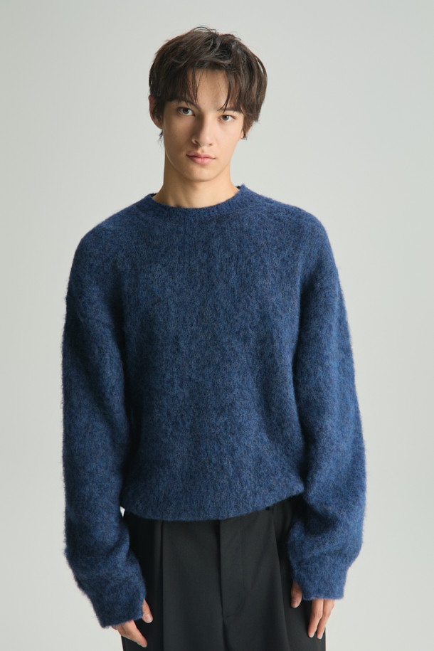 **Auras(오라스) 헤어리 니트 풀오버**는 부드러운 촉감과 따뜻함을 선사하는 겨울철 필수 아이템입니다. 오버핏 라운드넥 디자인으로 편안한 착용감을 제공하며, 헤어리한 표면감이 특징입니다. 아크릴, 알파카, 나일론, 모 소재 혼방으로 제작되어 보온성을 높였습니다. 네이비 컬러의 베이직 스타일로 집콕룩, 산책룩 등 다양한 TPO에 활용 가능하며, 클래식, 미니멀, 캐주얼 스타일을 연출하기 좋습니다. 두꺼운 두께감과 긴 소매 기장으로 겨울철에도 따뜻하게 입을 수 있습니다.
