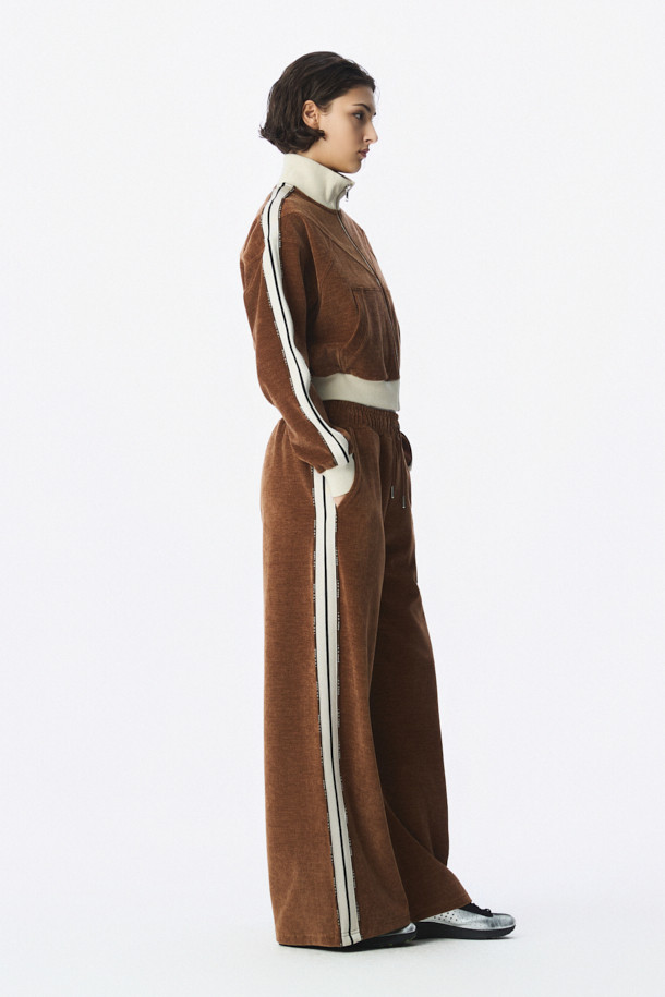 TRILLA 2.0 트랙 재킷은 여성용 아우터로, 봄/가을 계절에 활용하기 좋은 얇은 두께의 블루종 스타일 트랙 재킷입니다. 브라운 컬러에 하이넥 디자인과 옆선 로고 테이핑 디테일이 스포티하면서도 캐주얼한 무드를 연출합니다. 레귤러핏으로 제작되었으며, 집업 방식으로 간편하게 착용할 수 있습니다. 일상, 산책, 여행 등 다양한 TPO에 스타일리시하게 매치하여 캐주얼, 스포티, 미니멀 스타일을 완성할 수 있습니다. 긴 소매 기장의 폴리에스테르와 폴리우레탄 혼방 소재로 제작되었습니다.
