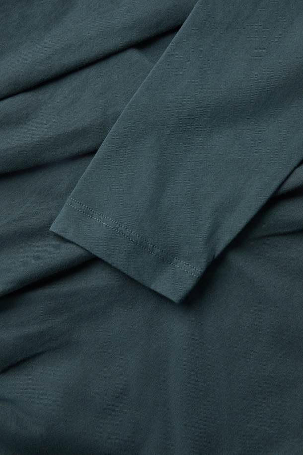 CAROLE(캐롤) 셔링 티셔츠는 여성스러운 실루엣을 연출하는 모던 스타일의 긴소매 티셔츠입니다. 부드러운 저지 소재로 제작되어 편안한 착용감을 선사하며, 라운드넥과 슬림핏 디자인으로 세련된 분위기를 더합니다. 크롭 기장과 셔링 디테일이 특징이며, 다크 그린 컬러가 시크한 매력을 자아냅니다. 데이트룩과 모임룩에 적합하며, 미니멀, 클래식, 시크 스타일을 즐겨 입는 분들께 추천합니다. 레이어드하여 다양한 스타일을 연출할 수 있습니다.
