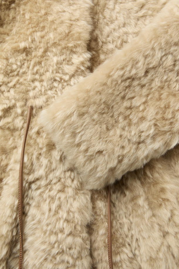 HURON(휴론) 시어링 하이넥 코트는 여성스러운 데이트룩을 완성하는 미니멀하고 시크한 스타일의 아우터입니다. 부드러운 촉감의 천연 양가죽과 레이온 혼방 소재로 제작되었으며, 두꺼운 두께감으로 겨울철에도 따뜻하게 착용할 수 있습니다. 허리 가죽 스트랩과 사이드 포켓, 스탠드 칼라 디테일이 돋보이며, 오버핏 디자인과 히든 클로징으로 세련된 실루엣을 연출합니다. 베이지 컬러의 무지 디자인으로 다양한 룩에 매치하기 용이합니다. 긴 소매 기장의 레귤러 기장 하이넥 코트로, 시크하고 세련된 겨울 스타일을 완성해 보세요.
