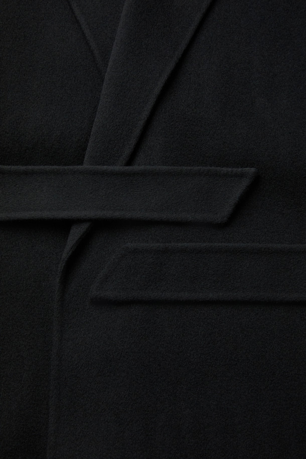 NALLIE(낼리) 오버 숄더 핸드메이드 울 코트는 여성들을 위한 클래식 스타일의 겨울 아우터입니다. 블랙 컬러의 무지 디자인으로, 출근룩, 오피스룩, 모임룩 등 다양한 TPO에 활용하기 좋습니다. 두꺼운 울 소재와 긴 소매 기장이 추운 날씨에도 따뜻함을 선사하며, 오버핏으로 편안한 착용감을 제공합니다. 핸드메이드 공정으로 제작되어 고급스러운 숄더 코트 타입이며, 더블 버튼과 허리 벨트, 라펠 디자인으로 세련된 멋을 더했습니다.
