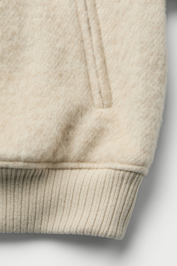 **Mousse(무스) 헤어리 하이넥 점퍼**는 겨울철 포근함을 선사하는 아우터입니다. 부드러운 촉감의 모, 아크릴, 폴리에스터, 나일론 혼방 소재로 제작되어 따뜻하고 편안한 착용감을 제공합니다. 오버핏 디자인에 하이넥 스타일로, 클래식, 미니멀, 캐주얼 등 다양한 스타일에 활용 가능하며, 출근룩으로도 손색없습니다. 안감은 폴리에스터를 사용하여 활동성을 높였으며, 니트 배색 디테일로 포인트를 더했습니다. 두꺼운 두께감으로 추운 날씨에도 든든하게 몸을 감싸줍니다.
