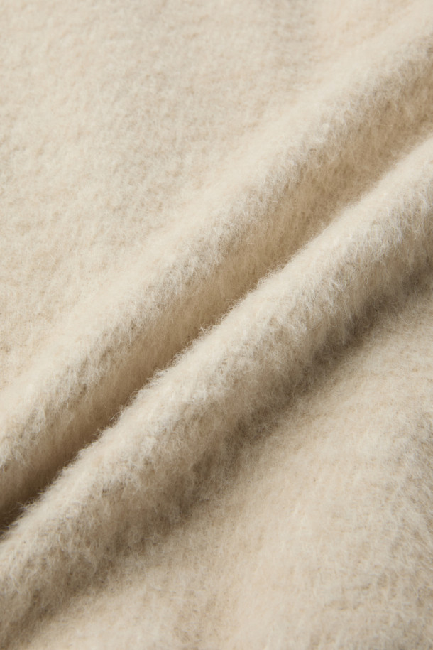 **Mousse(무스) 헤어리 하이넥 점퍼**는 겨울철 포근함을 선사하는 아우터입니다. 부드러운 촉감의 모, 아크릴, 폴리에스터, 나일론 혼방 소재로 제작되어 따뜻하고 편안한 착용감을 제공합니다. 오버핏 디자인에 하이넥 스타일로, 클래식, 미니멀, 캐주얼 등 다양한 스타일에 활용 가능하며, 출근룩으로도 손색없습니다. 안감은 폴리에스터를 사용하여 활동성을 높였으며, 니트 배색 디테일로 포인트를 더했습니다. 두꺼운 두께감으로 추운 날씨에도 든든하게 몸을 감싸줍니다.
