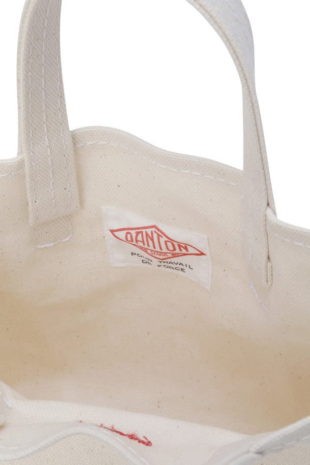 (DANTON) 캔버스 토트백 - 보쥬 쁘띠 에크루(레드)는 18온스 캔버스 소재로 제작되어 튼튼함을 자랑하는 여성용 토트백입니다. 에크루와 레드의 조화가 돋보이며, 사각 모양에 화이트 스티치 디테일이 더해져 미니멀하고 클래식한 스타일을 연출합니다. 가방 전면에 로고 자수 디테일이 포인트로 들어가 있으며, 오픈형 디자인으로 내부 수납이 용이합니다. 데이트룩이나 쇼핑룩에 잘 어울리는 미디엄 사이즈의 무지 토트백으로, 내부 포켓은 없습니다.
