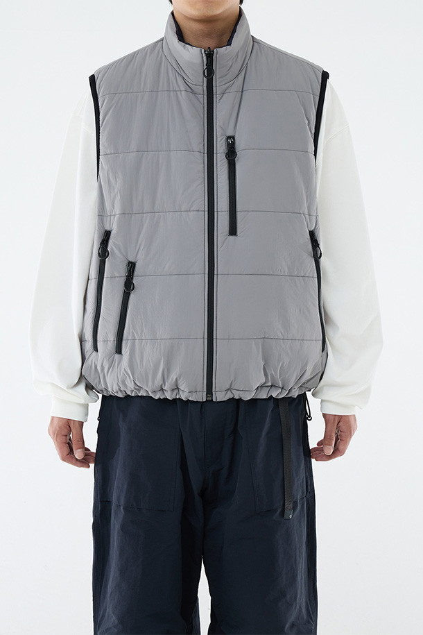 **REVERSIBLE PUFF VEST - CLOUD GRAY/NAVY (리버서블 패딩 베스트 - 클라우드 그레이/네이비)**

클라우드 그레이와 네이비 컬러 양면으로 착용 가능한 남성용 리버서블 패딩 베스트입니다. 가을, 겨울 시즌에 적합하며, 캐주얼 및 스포티 스타일을 연출할 수 있습니다. 넉넉한 루즈핏으로 편안한 착용감을 제공하며, 지퍼형 여밈과 스탠드 카라 디자인으로 보온성을 높였습니다. 방수, 보온, 통기 기능에 신슐레이트 충전재를 사용하여 한겨울에도 따뜻하게 입을 수 있습니다. 일상, 산책, 여행 등 다양한 TPO에 활용하기 좋은 아이템입니다.
