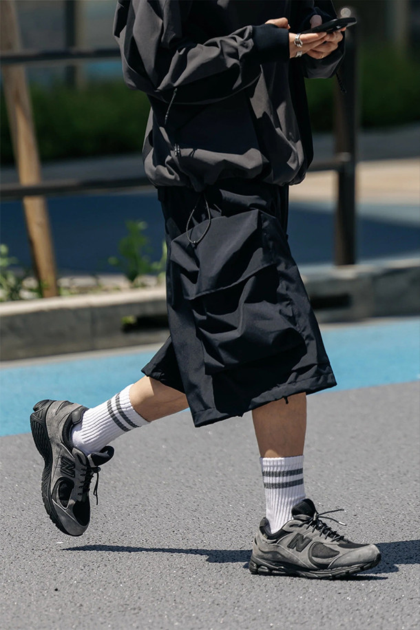 (CLESSTE) 고어텍스 랩스 시티 밀리터리 하프 팬츠 002 - 블랙은 봄, 여름 시즌에 적합한 남성용 하프 팬츠입니다. 고어텍스 소재를 사용하여 방풍, 투습, 발수 기능을 갖추어 쾌적함을 유지하며, 밀리터리 & 스포티 스타일을 연출합니다. 카고 팬츠 위에 덧입는 오버 팬츠 디자인으로 옆선 앞쪽 비틀림 디테일이 특징이며, 허리 고무밴드와 드로코드, 밑단 조절 장치로 편안한 착용감을 제공합니다. 레귤러핏으로 제작되었으며, 여행룩, 캠핑룩, 고프코어 및 미니멀, 스포티 스타일을 즐기는 분들에게 적합합니다.
