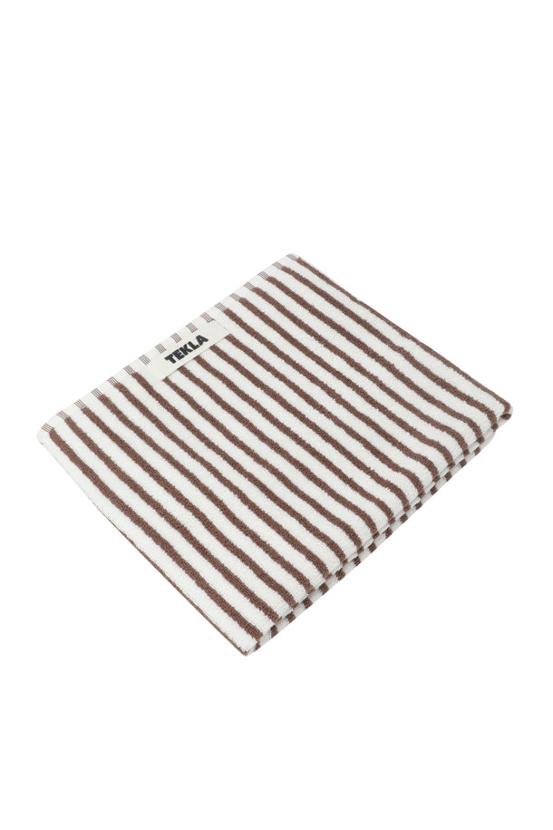 테리 핸드 타월 (세일러 스트라이프) 50X90 - 코디악 스트라이프는 부드러운 면 소재로 제작되어 뛰어난 흡습력을 자랑하는 욕실용 타월입니다. 화이트와 브라운 컬러의 세일러 스트라이프 패턴이 시원하고 산뜻한 분위기를 연출합니다. 보통 두께감으로 제작되었으며, 부드러운 촉감이 특징입니다. 깔끔한 디자인을 위해 더블 스티치 처리된 밑단과 견고한 모서리 마감, 행거 루프가 적용되었습니다. Oeko-Tex® Standard 100 인증을 받아 안심하고 사용할 수 있습니다.
