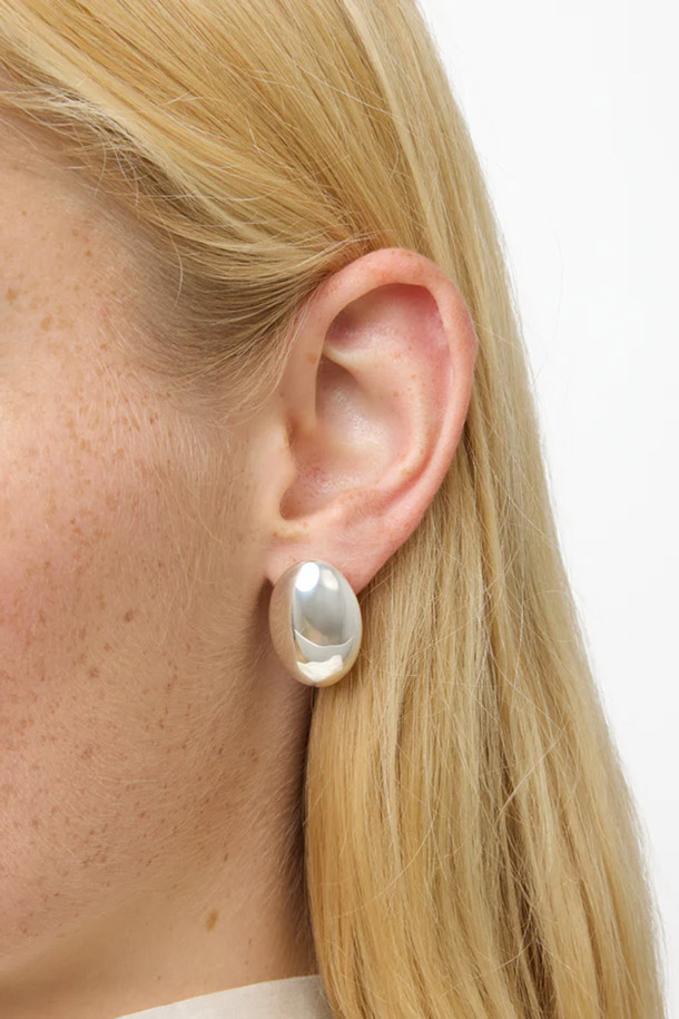 LIE STUDIO (리 스튜디오)의 THE CAMILLE EARRINGS (카밀 귀걸이) - 실버는 미니멀하고 베이직한 스타일을 추구하는 여성들을 위한 귀걸이입니다. 925 스털링 실버 소재로 제작되어 은은하게 빛나며, 저자극성으로 안심하고 착용할 수 있습니다. 타원형 디자인으로 세련된 느낌을 더하며, 데이트룩, 모임룩, 소개팅룩 등 다양한 TPO에 잘 어울립니다. 약 8g의 가벼운 무게와 2.5cm의 길이로 편안한 착용감을 선사하며, 물, 향수, 화학 제품과의 접촉을 피하고 부드러운 천으로 닦아 관리하면 오랫동안 아름다움을 유지할 수 있습니다.
