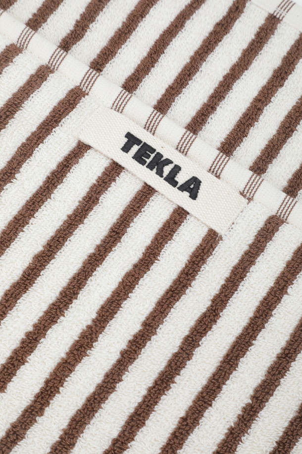 테리 핸드 타월 (세일러 스트라이프) 50X90 - 코디악 스트라이프는 부드러운 면 소재로 제작되어 뛰어난 흡습력을 자랑하는 욕실용 타월입니다. 화이트와 브라운 컬러의 세일러 스트라이프 패턴이 시원하고 산뜻한 분위기를 연출합니다. 보통 두께감으로 제작되었으며, 부드러운 촉감이 특징입니다. 깔끔한 디자인을 위해 더블 스티치 처리된 밑단과 견고한 모서리 마감, 행거 루프가 적용되었습니다. Oeko-Tex® Standard 100 인증을 받아 안심하고 사용할 수 있습니다.
