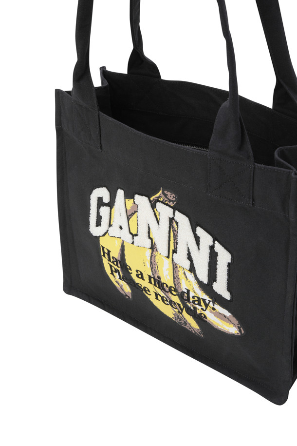 라지 이지 쇼퍼 바나나 프린트 - 블랙은 캔버스 소재의 여성용 쇼퍼백입니다. 블랙 컬러 바탕에 바나나 프린트와 브랜드 레터링 자수 디테일이 돋보이며, 캐주얼하고 미니멀한 스타일을 연출합니다. 넉넉한 라지 사이즈로 수납력을 높였으며, 오픈형 잠금 방식으로 편리하게 사용할 수 있습니다. 일상과 쇼핑, 동네 마실룩에 잘 어울리는 실용적인 가방입니다.
