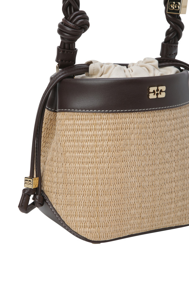 "Bou Bucket Bag - Tobacco Brown"은 라탄 소재의 스몰 사이즈 버킷백으로, 매듭 손잡이와 GANNI Butterfly 하드웨어 로고가 특징입니다. 캐주얼한 스타일에 끈 잠금 방식으로 디자인되었으며, 일상생활에서 편안하게 사용할 수 있습니다. 세련된 토바코 브라운 컬러는 어떤 스타일에도 잘 어울립니다.

